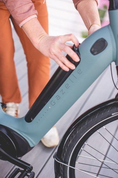 Eine Person schaltet das Elektrofahrrad an, während sie auf der Straße steht.